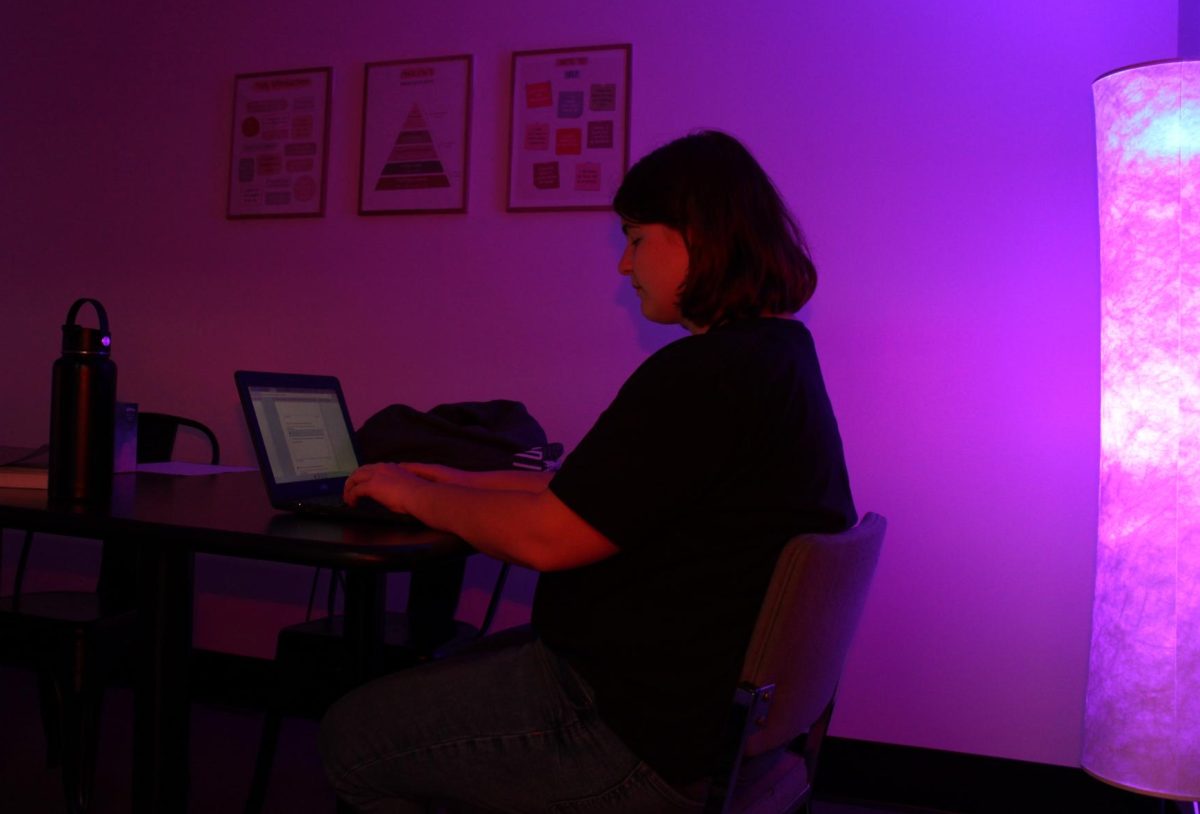 Senior Cora Tolbert takes a mental health break, supported by ambient mood lighting, in the guidance office's Recharge Room.