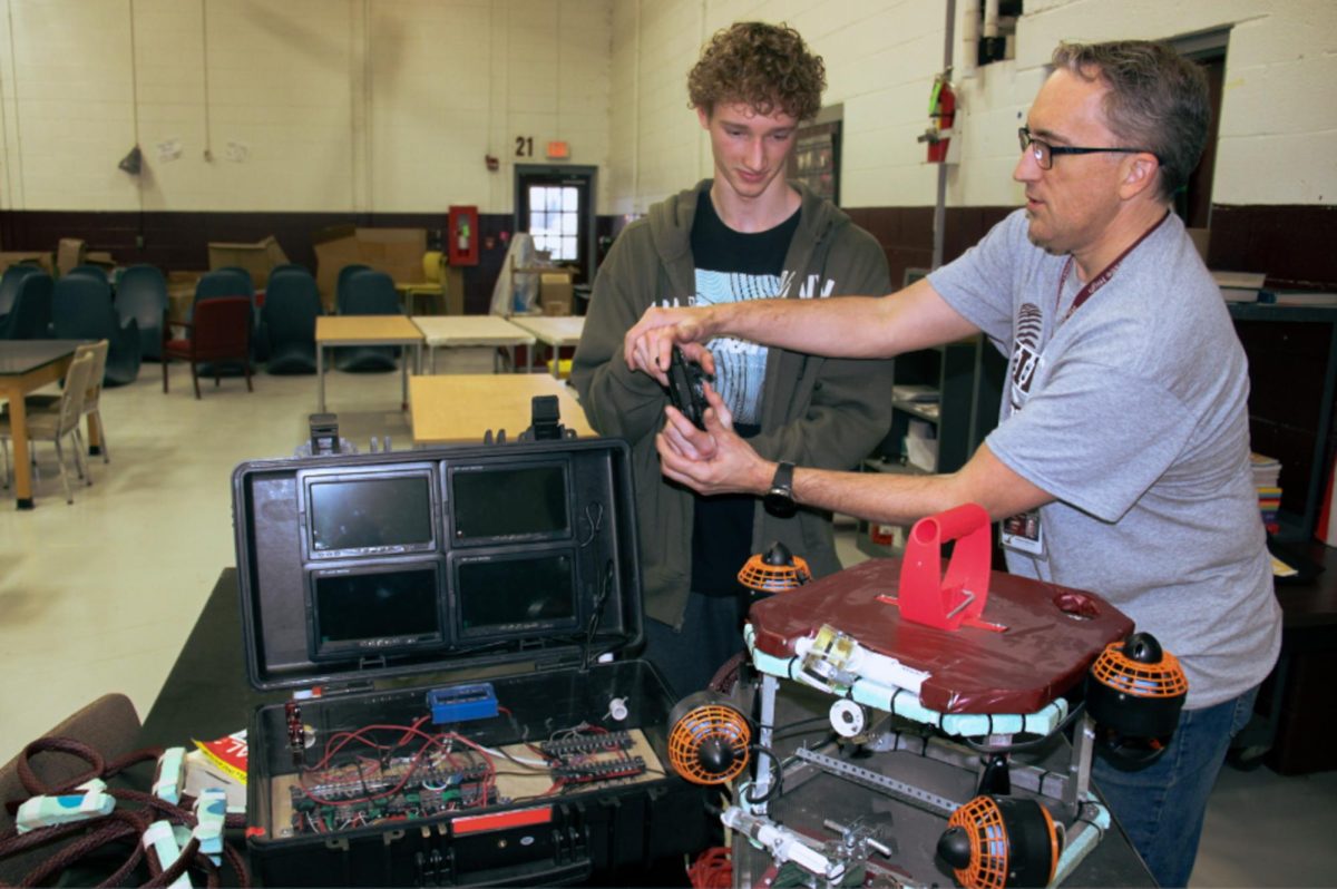 Advisor Benji Lewis assists junior member Ian Jesse in handling the controls to the Underwater ROV.