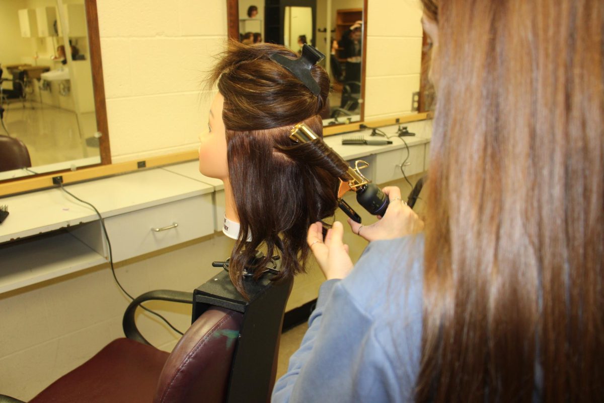 Sophomore Amy Hicks is seen curling a mannequins' hair during her Cosmetology class.