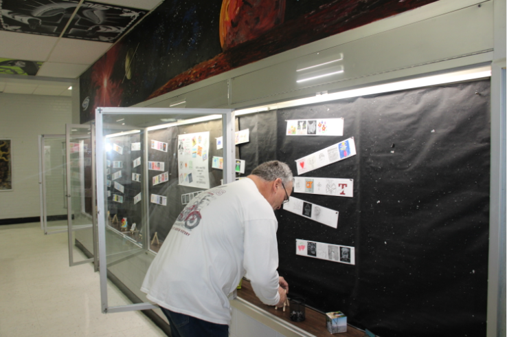 Art Club sponsor Anthony Graham hanging new artworks in display glass.