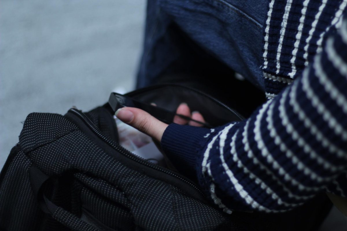 A student reaches into their backpack to check the time.