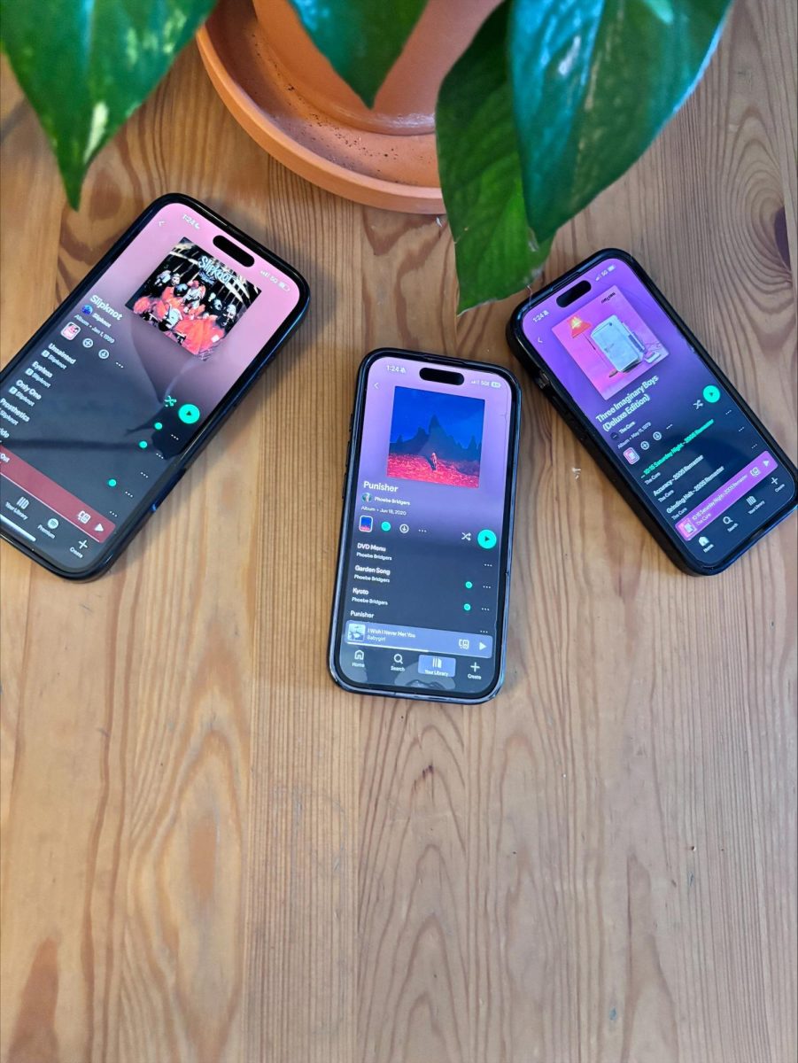 A group of students' phones opened to Spotify, showing albums they enjoy.