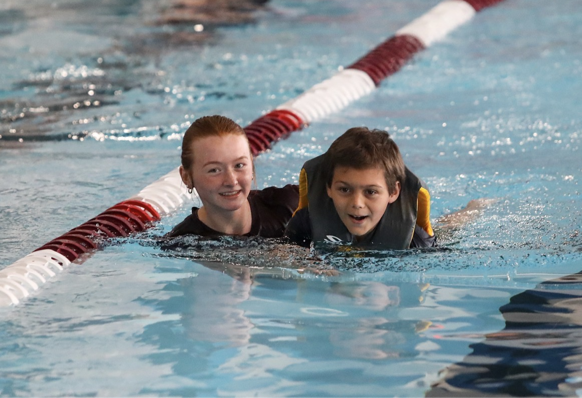 Peer tutor Sydney Clark helps a student swim across the pool, allowing him to reach the finish line.