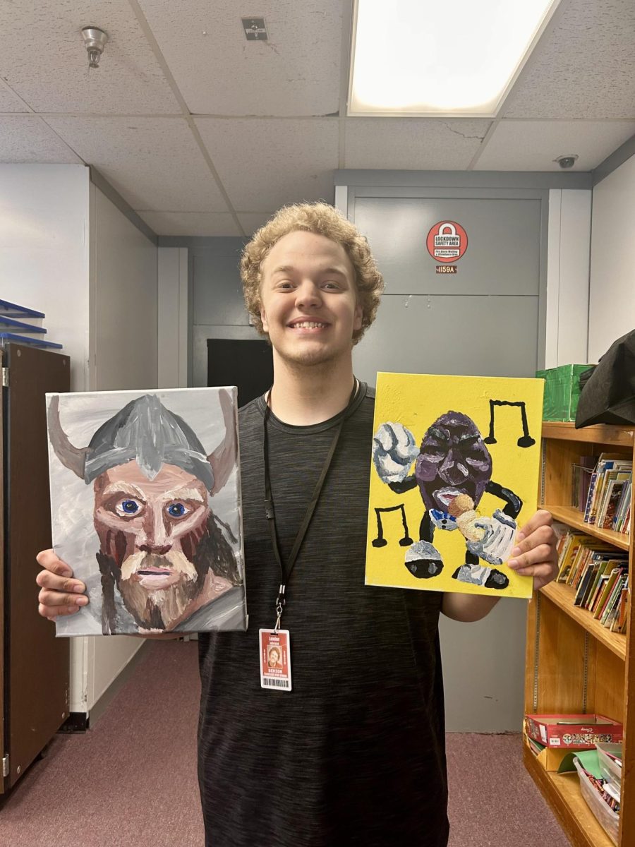 Landon Johnson poses with some of his recent paintings, including a painting of a Viking.